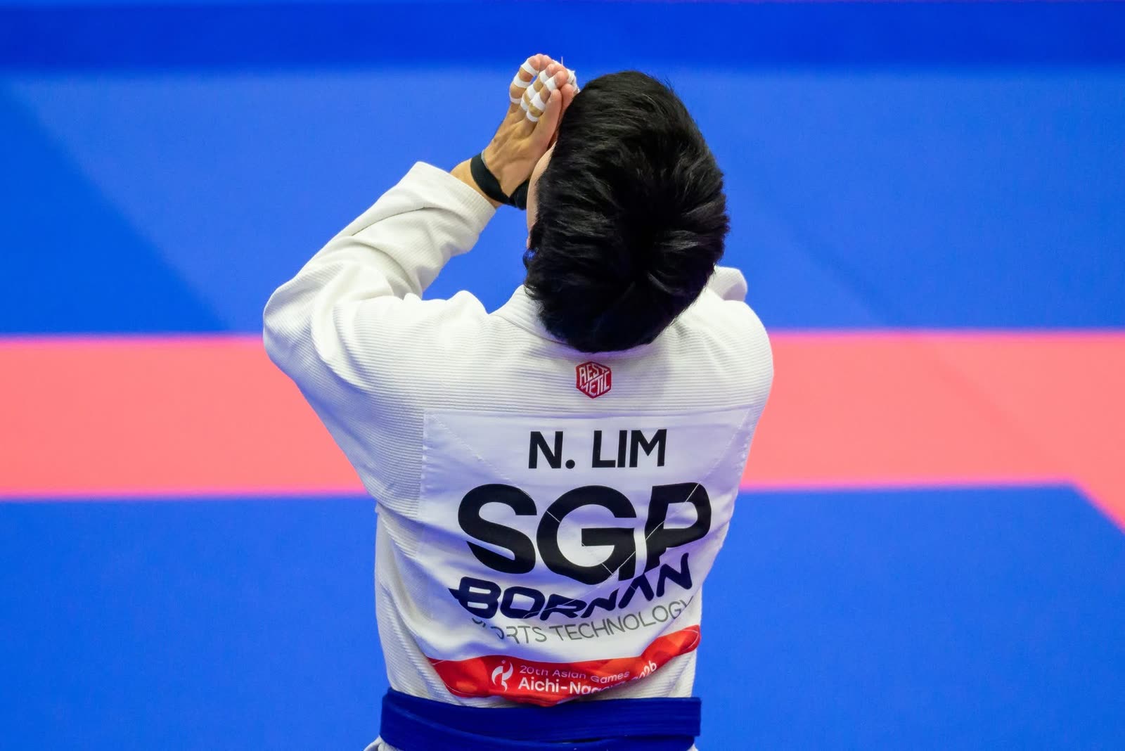 Noah Lim seen from behind, his gi printed with N. LIM and SGP