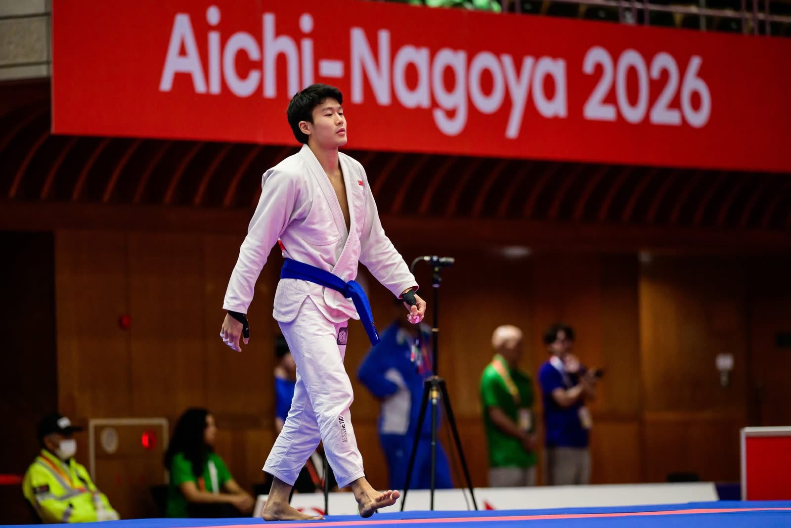 Noah Lim walking onto the mat beneath an Aichi-Nagoya 2026 banner at the Asian Games